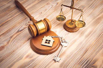 Judge gavel and house key on wooden background.