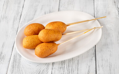 Corn dogs on white serving plate