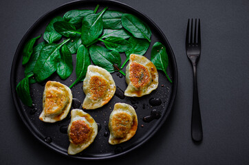 Dumplings with fresh spinach in a black plate