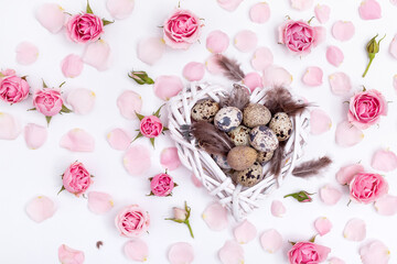 Flatlay Easter composition with quail eggs, feathers and roses