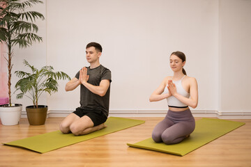 Obraz premium Sporty pair practicing yoga together at home