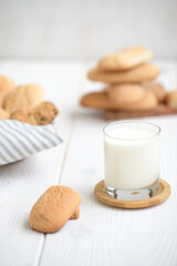 Freshly baked homemade crunchy cookies with glass of milk. A delicious treat for gourmets, sweet breakfast. Biscuits on a white wooden background