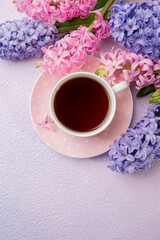 A cup of tea with flowers hyacinths on a pink-lilac background. Idea. spring background, concept. Top view.