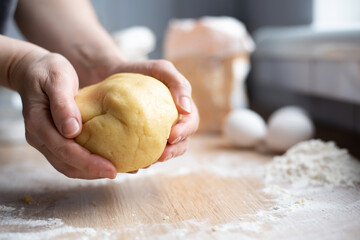 Female hands holding a bowl of cookie dough in the kitchen, cooking cookies at home.