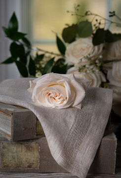 Ivory rose on a napkin with a bouquet of roses behind. 