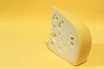Close-up of gruyere cheese isolated on yellow background.