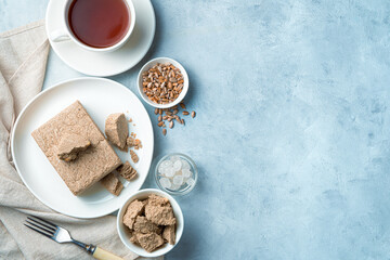 Halva with seeds and tea on a light blue background. Top view with copy space.
