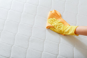 Employee cleans surface of mattress on bed with rag. Cleaning disinfection surfaces. Cleaning...