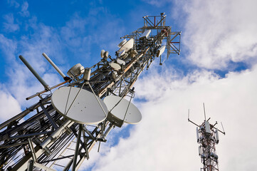 Two towers of communications with antennas against deep blue sky
