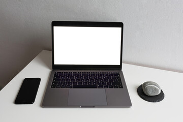 Stylish monochrome minimal workspace with laptop, black mobile and stone on a white table and against a white wall background