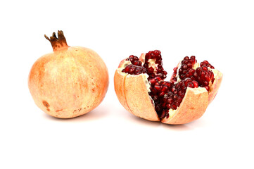 An unpeeled pomegranate next to a ripe red pomegranate cut into slices.