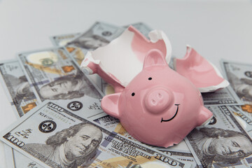 Investment and bankruptcy concept. Broken piggy bank on dollar banknotes close-up