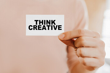 Man holding a business card with Think Creative