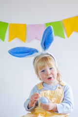 Adorable little boy in bunny ears with easter eggs on a festive day
