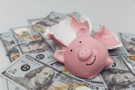 Investment and bankruptcy concept. Broken piggy bank on dollar banknotes close-up