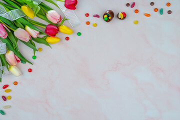 Fresh tulips and decorative Easter eggs on pink marble