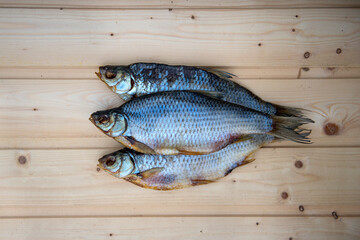 Dried fish roach on a light wooden table. Beer snack. Image of air-dried salted fish. Dried fish. Salty beer appetizer. Traditional way of preserving fish. Dried salted roach top view