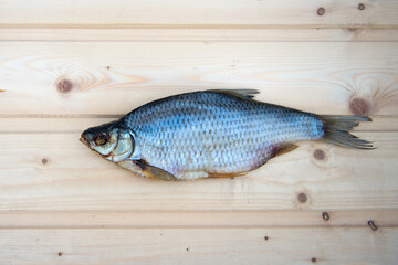 Dried fish roach on a light wooden table. Beer snack. Image of air-dried salted fish. Dried fish. One dried or jerky salted roach, tasty clipfish on wooden background. Salty beer appetizer.