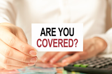 a woman in a white shirt holds a piece of paper with the text: are you covered, business concept.
