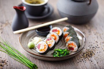 Sushi maki rolls with tuna, flying fish caviar, crab, avocado on a plate with chopsticks, soy sauce, wasabi and ginger. Japanese traditional food closeup served for lunch in modern gourmet restaurant