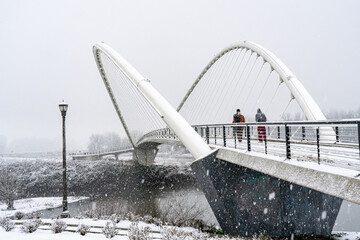 During a snowstrom, two people walking accross  the Peter Courtney Minto Island Bridge, it connects Salem's Riverfront park to Minto Brown Park, Salem, Oregon
