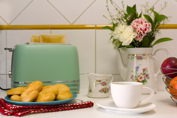 Breakfast table with toasted bread, cookies, coffee and fresh flowers