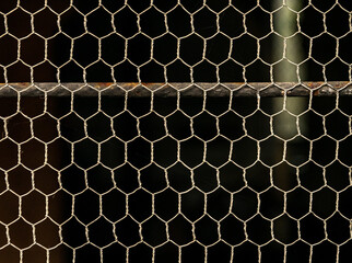 Reja, valla o red metálica en forma de hexágono sobre un fondo negro
