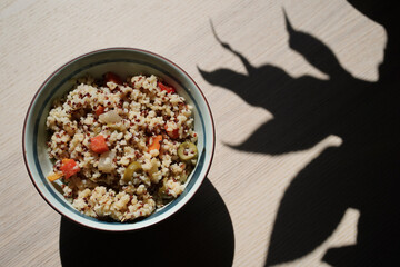 Italian quinoa salad with a bell pepper, green olives, tomatoes - vegetarian, vegan food, shadow of a tree, plant, artistic shot