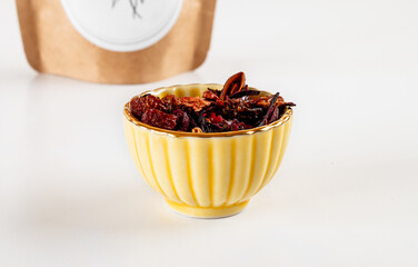 Red fruit tea in a yellow cup with a brown paper bag in the back.