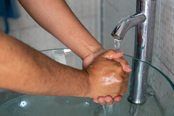 Hombre lavandose las manos en el baño, higiene y prevencion.