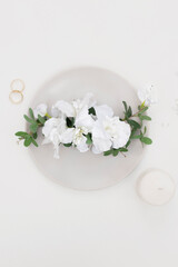 Obraz na płótnie Canvas bridal flower crown. wedding accessories. White bridal flowers two gold wedding rings and a candle on white background