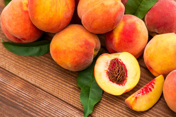 Ripe peaches and leaves on wooden table. Fresh fruits peaches with leaves on a wooden background