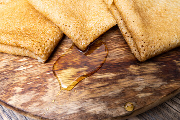 a drop of honey on a wooden tray with pancakes
