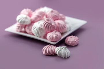 Pink and white meringue on a white plate. Pink background. Place for your text. High quality photo