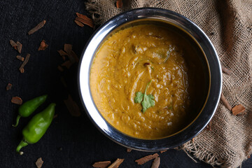 Chicken haleem in bowl with chilis, indian cusine on black background