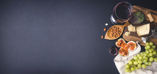 Wine and snacks background. Wine, cheese, fruits on a dark background. Food and wine banner