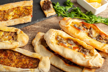 Kasarli sucuklu pide and kiymali pide are traditional Turkish flatbreads similar to pizza with meat and cheese toppings. They are served with lemon and parsley.