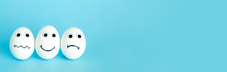 Fun creative food for kids. Eggs minimal concept. White funny eggs for breakfast on a colored blue banner background