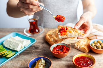 Healthy Turkish breakfast, with sliced tomato, cucumber, and white feta cheese, small bowls of strawberry jam, olive, honey, pepper paste. Tea is served in traditional Turkish tea glass. Ramadan feast