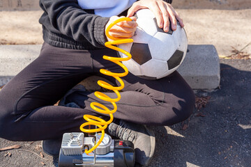 Close up image showing a caucasian woman holding a soccer ball and inserting needle bit at the end...
