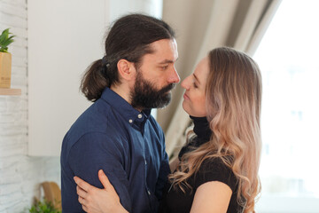 Man embracing pregnant partner in kitchen.