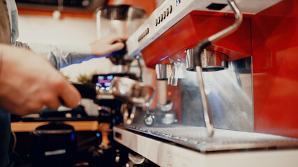 The barista makes coffee americano, espresso, cappuccino in the coffee machine. Works in his small business restaurant cafe. Clothing apron uniform of the bar staff. Copy space. Modern interior.