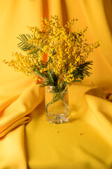 draped yellow background texture fabric with glass and mimosa