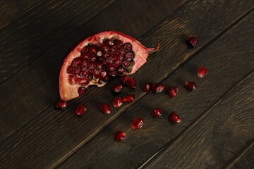 A slice of pomegranate with scattered grains next to it .