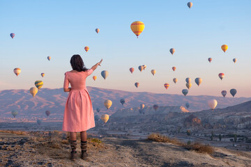 Hot air balloons over Cappadocia, a girl in a pink dress shows a balloon