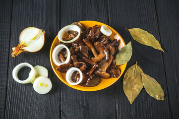 Armillaria mellea or honey fungus marinated in a yellow plate with spices and onions on a vintage table. Idea for a delicious snack for lunch. Top view