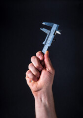 Worker hand holds caliper on a dark background. Idea for building or renovation