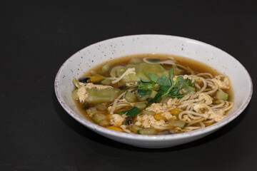 Hot soup with Coconut nut milk, chiken, pasta and vegetable on a black background