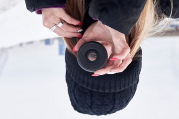 A young girl in black clothes holds a photo lens with an inverted image - her eye.