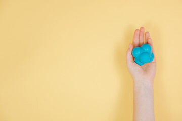 A hand is holding a massage and reactivity ball. Ball for physiotherapy on a yellow background. Self-massage for muscles. 